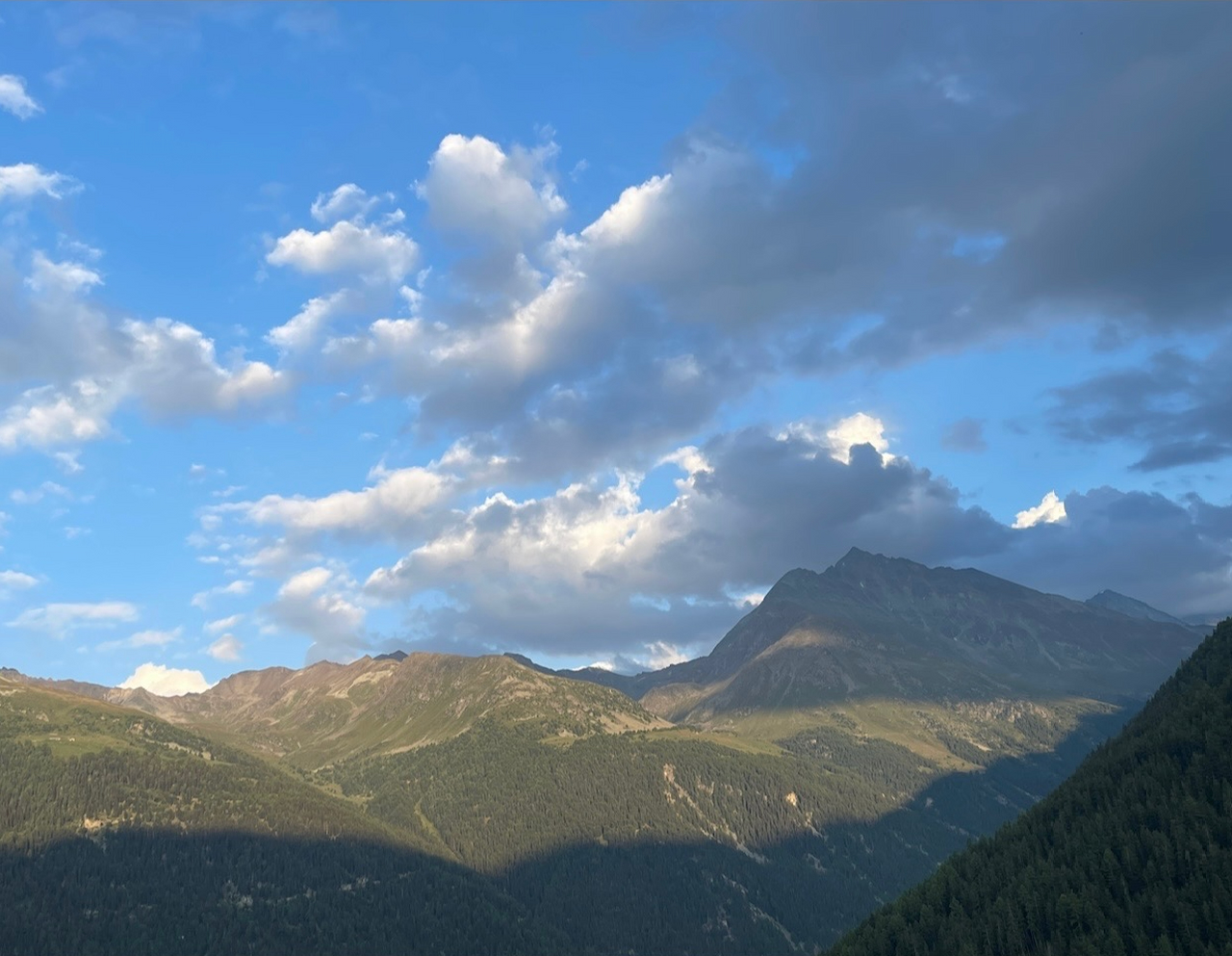 Vue des montagnes des Alpes Valaisannes sous un ciel bleu parsemé de nuages au coucher du soleil